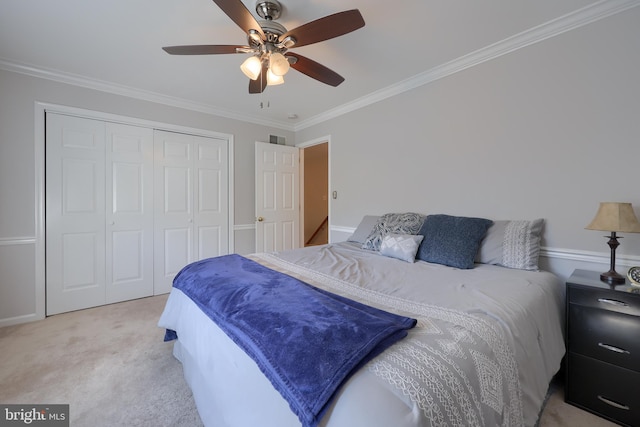 bedroom with ceiling fan, ornamental molding, light carpet, and a closet