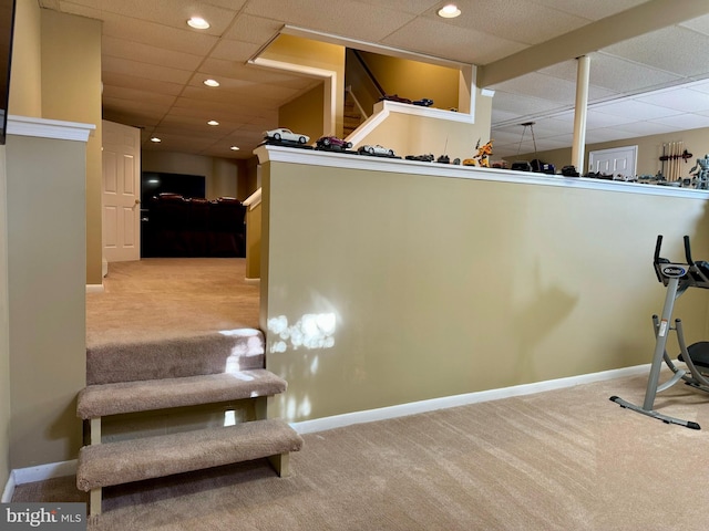 workout room with a paneled ceiling and light colored carpet