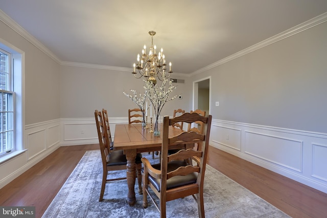 dining room with crown molding, hardwood / wood-style floors, and a chandelier