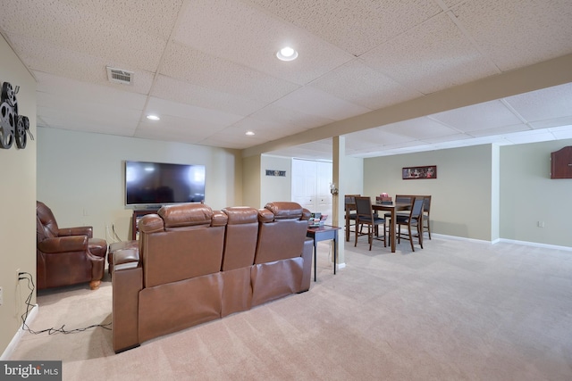 living room featuring light carpet and a drop ceiling