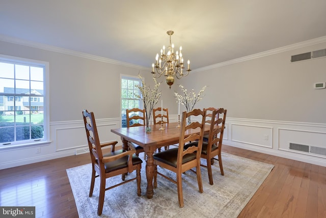 dining space with crown molding, wood-type flooring, and a notable chandelier