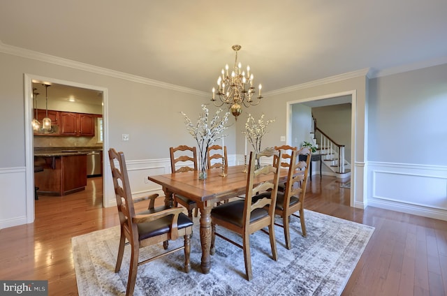 dining area with crown molding, wood-type flooring, and an inviting chandelier