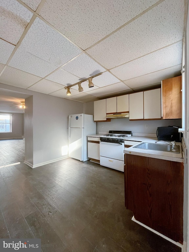 kitchen with a drop ceiling, white appliances, and sink