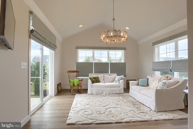 living room featuring a wealth of natural light, an inviting chandelier, vaulted ceiling, and light wood-type flooring