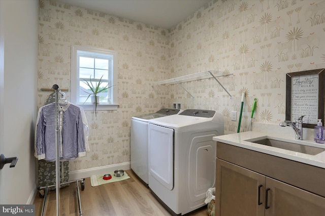 washroom with cabinets, light wood-type flooring, separate washer and dryer, and sink