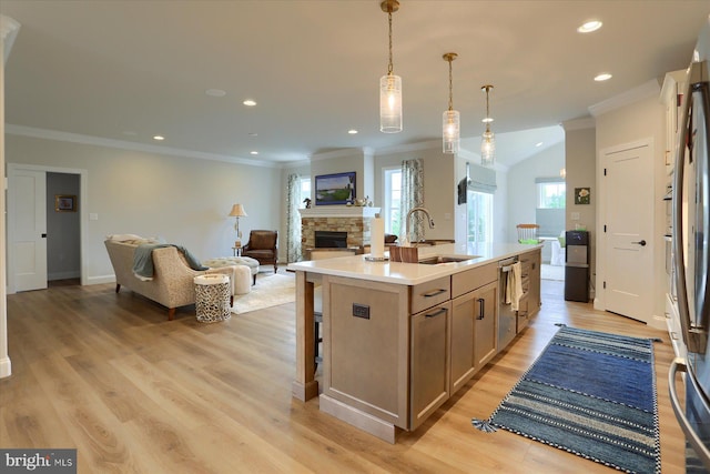 kitchen with a kitchen island with sink, sink, appliances with stainless steel finishes, decorative light fixtures, and light hardwood / wood-style floors