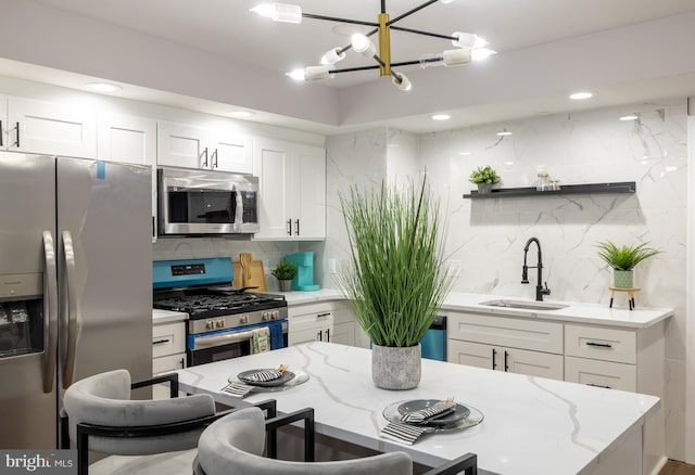 kitchen with decorative backsplash, light stone counters, stainless steel appliances, sink, and white cabinetry