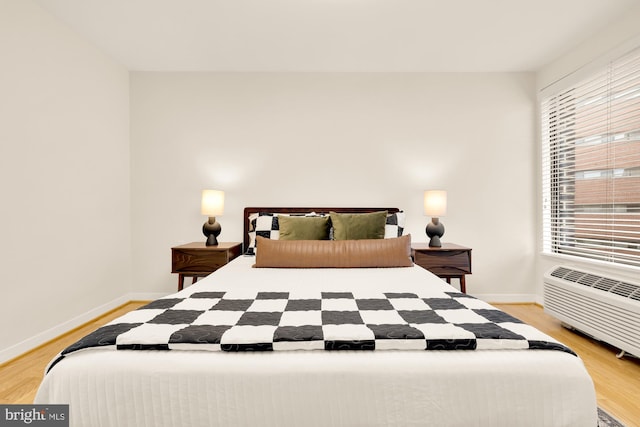 bedroom featuring a wall mounted AC and light hardwood / wood-style flooring