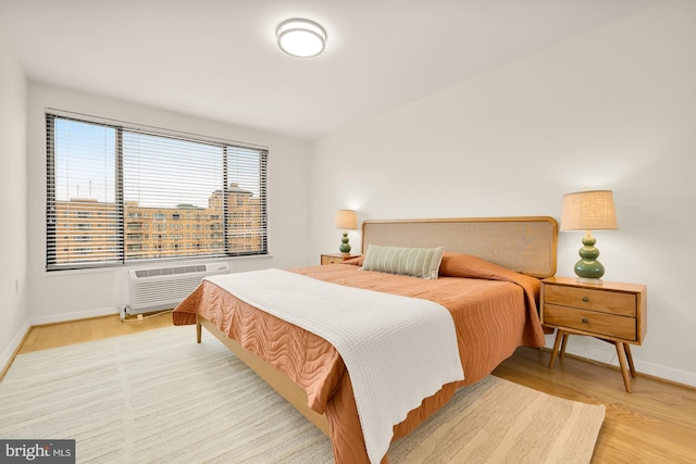 bedroom featuring light hardwood / wood-style floors and a wall mounted AC