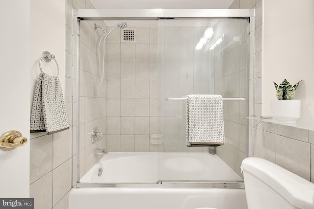 bathroom with bath / shower combo with glass door and toilet