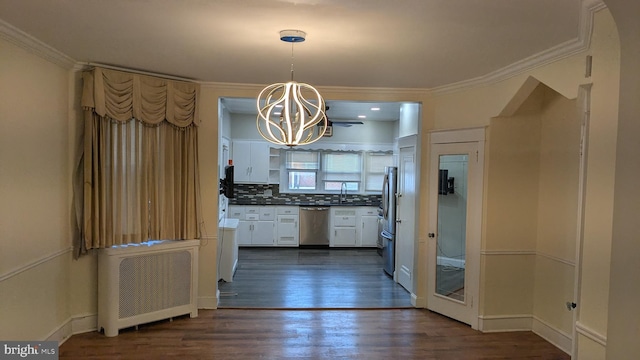 kitchen with sink, radiator heating unit, backsplash, decorative light fixtures, and appliances with stainless steel finishes