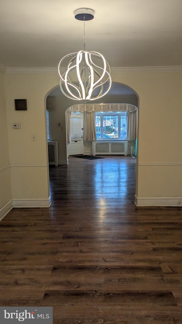 unfurnished dining area with a chandelier, dark hardwood / wood-style flooring, radiator, and ornamental molding