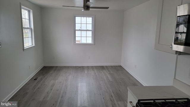 empty room with ceiling fan and light hardwood / wood-style floors