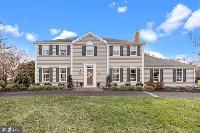 colonial-style house featuring a front lawn