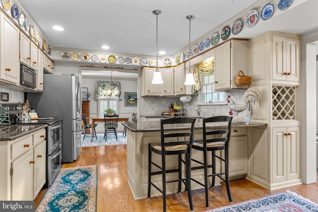 kitchen with double oven range, a kitchen bar, black microwave, and dark stone counters