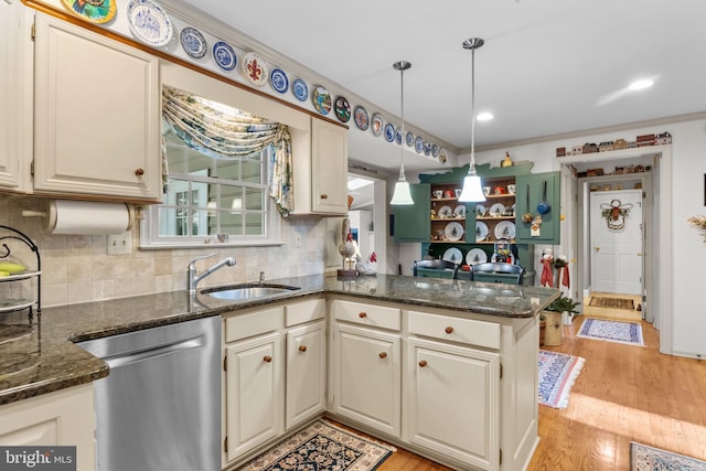 kitchen featuring dishwasher, sink, kitchen peninsula, dark stone countertops, and light wood-type flooring