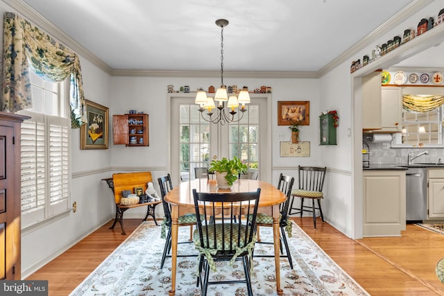 dining room with light hardwood / wood-style floors, ornamental molding, a wealth of natural light, and a chandelier