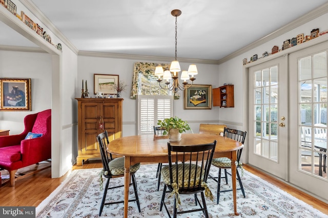 dining room featuring ornamental molding, french doors, a chandelier, and light hardwood / wood-style floors