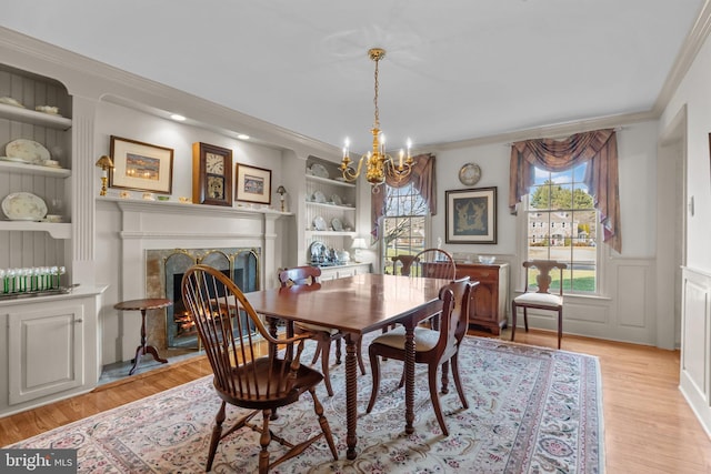 dining room with built in features, light hardwood / wood-style floors, and ornamental molding