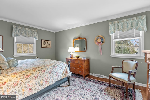 bedroom with multiple windows, crown molding, and light wood-type flooring