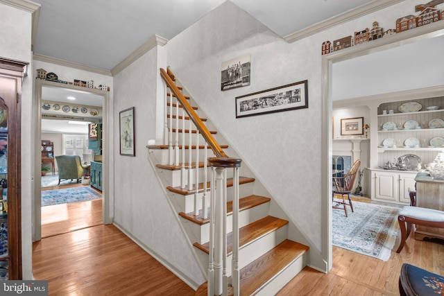 staircase with ornamental molding and hardwood / wood-style flooring