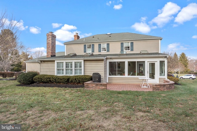 rear view of property with a lawn, a patio area, and a sunroom