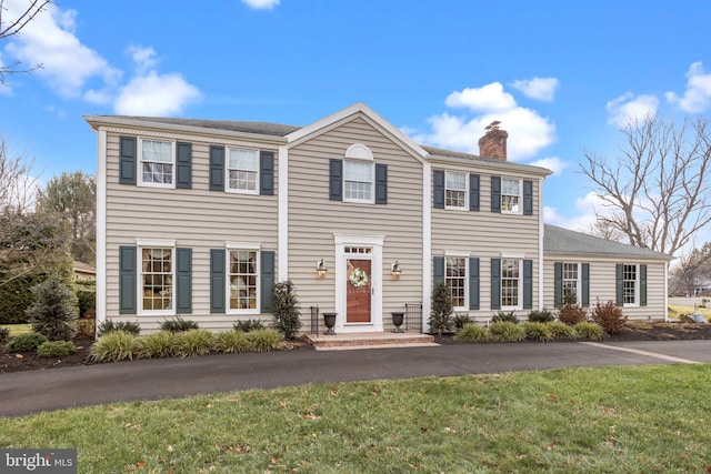 colonial home featuring a front lawn