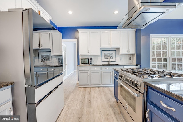 kitchen with refrigerator with ice dispenser, white cabinets, high end stainless steel range oven, and extractor fan