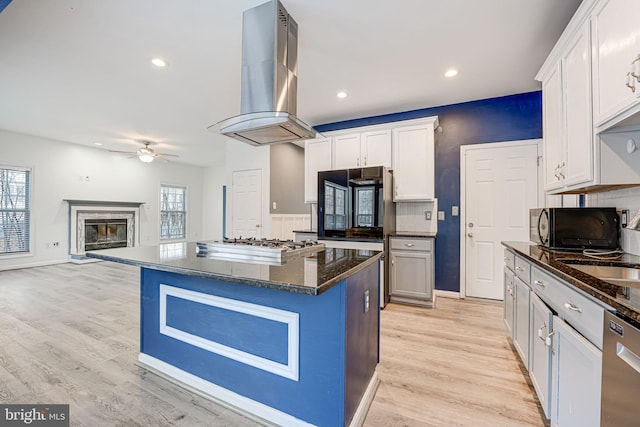 kitchen featuring dark stone counters, stainless steel appliances, extractor fan, a center island, and white cabinetry