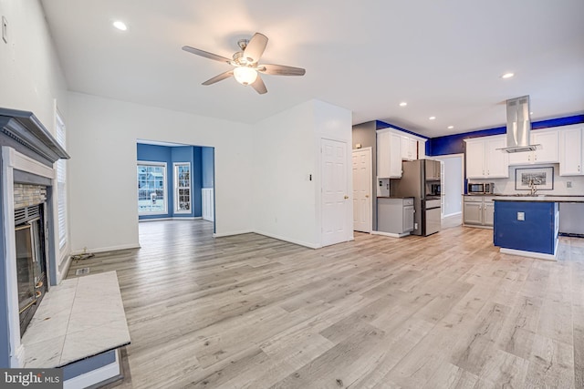 unfurnished living room featuring light hardwood / wood-style floors, ceiling fan, and sink