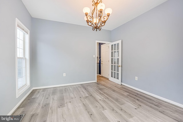 empty room featuring light hardwood / wood-style flooring, a wealth of natural light, and an inviting chandelier