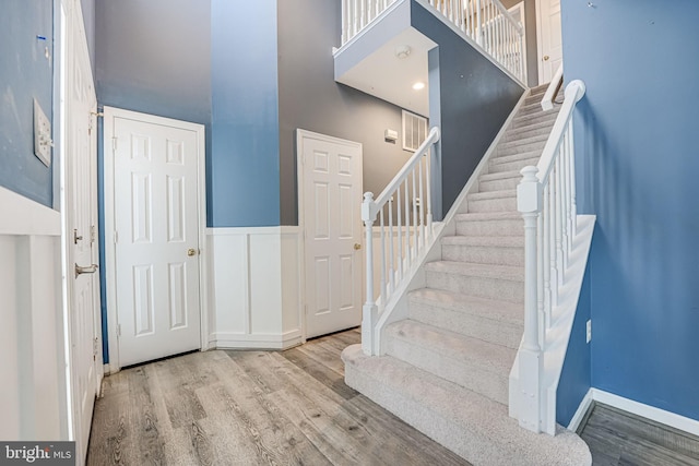 staircase featuring a towering ceiling and hardwood / wood-style flooring