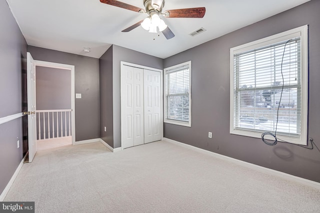 unfurnished bedroom featuring ceiling fan, light colored carpet, and a closet