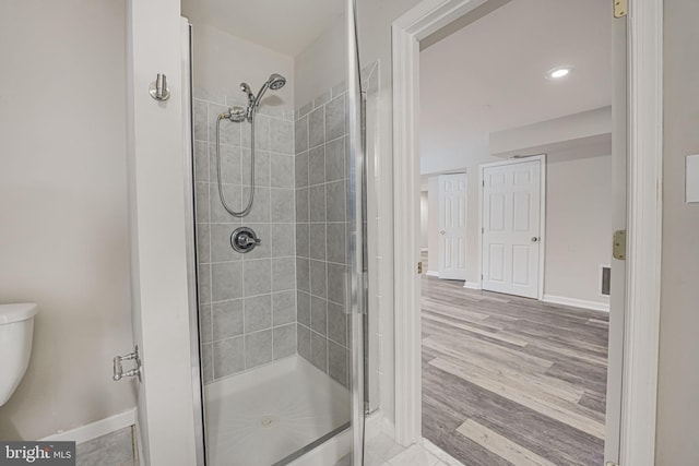 bathroom featuring hardwood / wood-style flooring, toilet, and a shower with shower door