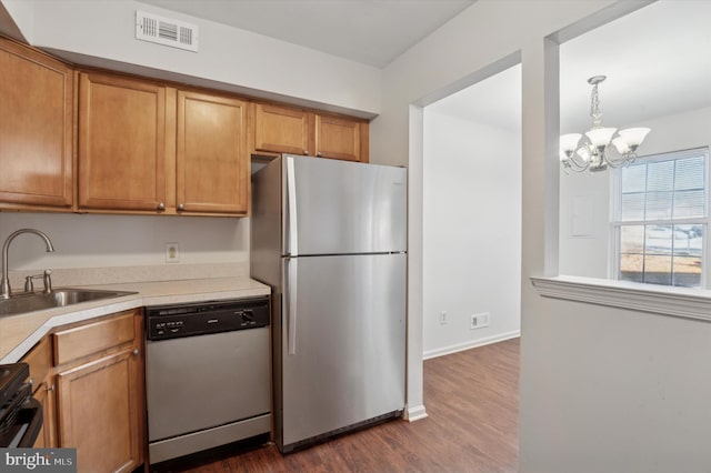 kitchen with stainless steel appliances, dark wood-type flooring, sink, a notable chandelier, and hanging light fixtures