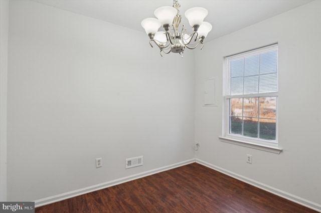 empty room featuring dark wood-type flooring and a notable chandelier