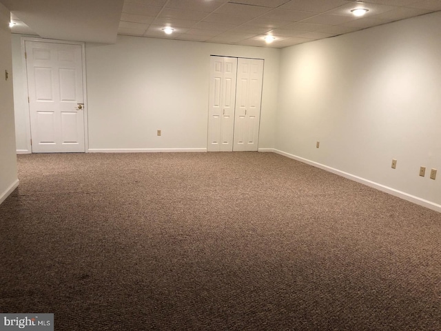 empty room featuring dark colored carpet and a paneled ceiling