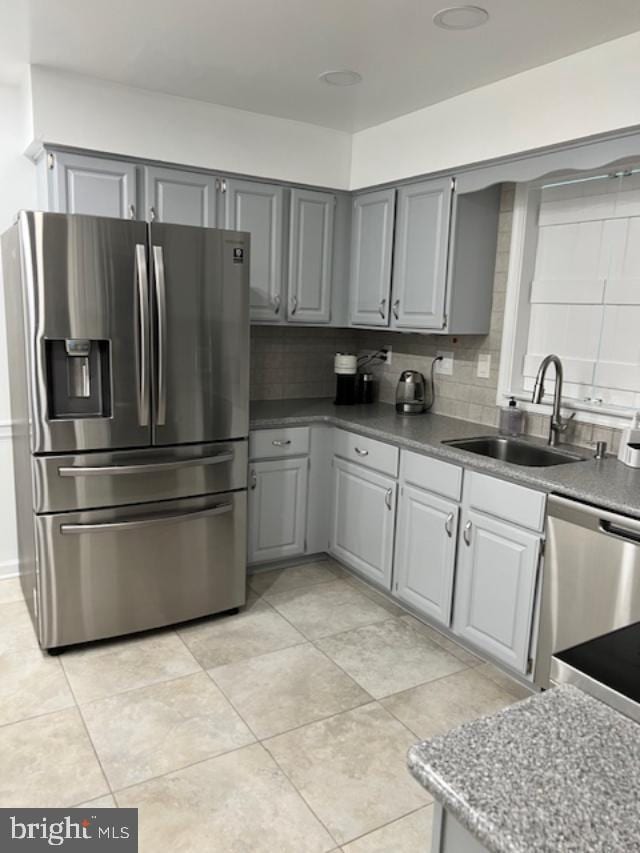 kitchen with decorative backsplash, stainless steel appliances, sink, gray cabinets, and light tile patterned flooring