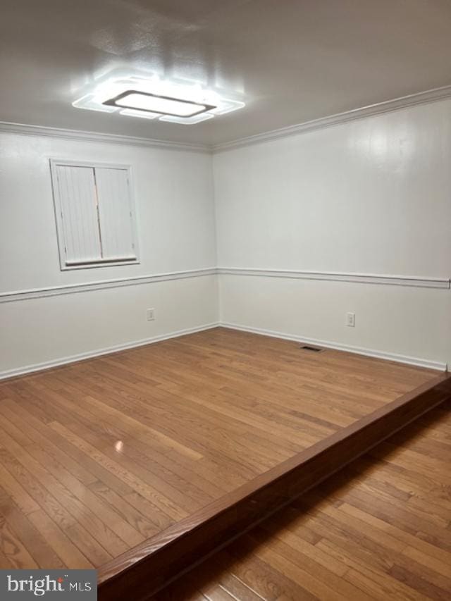 unfurnished room with hardwood / wood-style flooring and ornamental molding