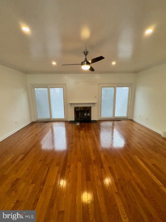 unfurnished living room featuring hardwood / wood-style floors, plenty of natural light, and ceiling fan