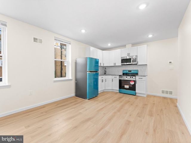 kitchen featuring light hardwood / wood-style floors, white cabinetry, appliances with stainless steel finishes, and tasteful backsplash