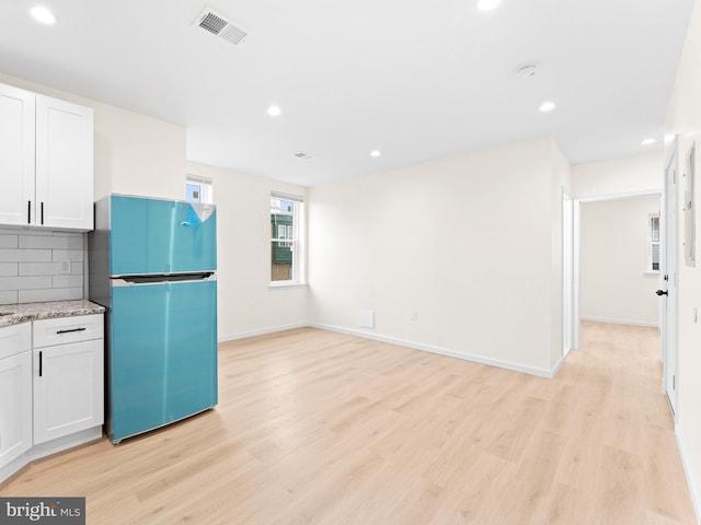 kitchen with white cabinetry, stainless steel refrigerator, tasteful backsplash, and light hardwood / wood-style flooring