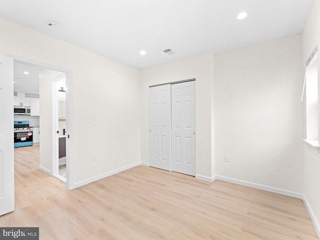 unfurnished bedroom featuring light hardwood / wood-style flooring and a closet