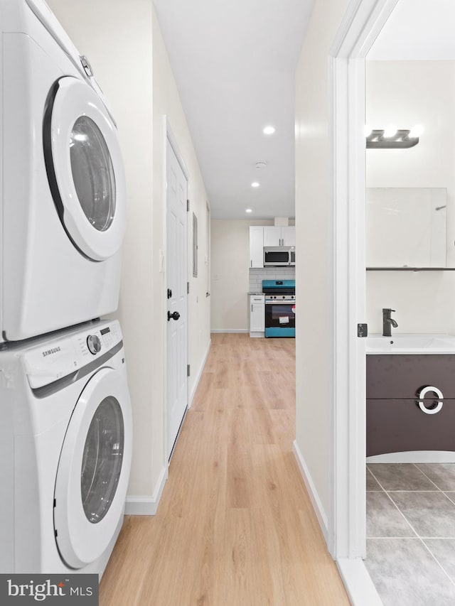 clothes washing area with light wood-type flooring, stacked washer / dryer, and sink