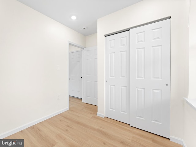 unfurnished bedroom with light wood-type flooring and a closet