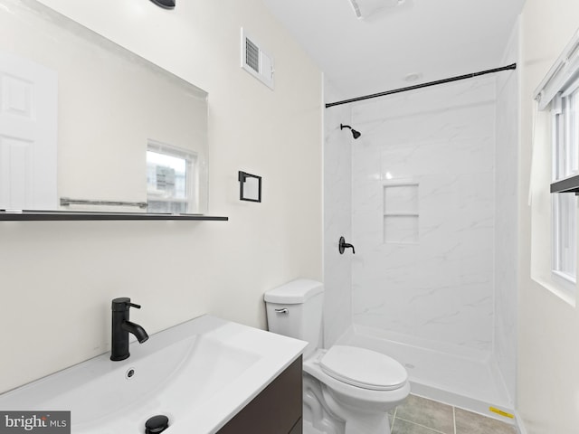 bathroom featuring tile patterned flooring, vanity, toilet, and a tile shower