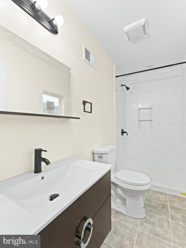 bathroom featuring a tile shower, vanity, toilet, and tile patterned floors