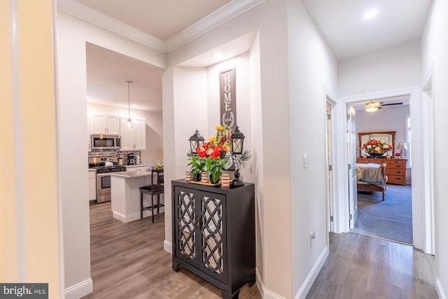 hall with light hardwood / wood-style floors and ornamental molding