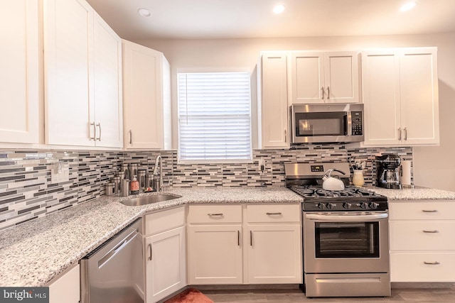 kitchen featuring decorative backsplash, sink, white cabinetry, and stainless steel appliances