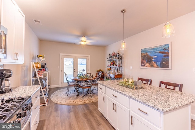 kitchen featuring a center island, french doors, hanging light fixtures, light hardwood / wood-style floors, and white cabinets